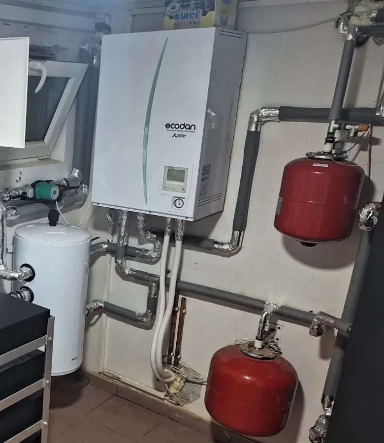 Indoor unit of a heat pump in a boiler room, with a water heater and expansion tanks